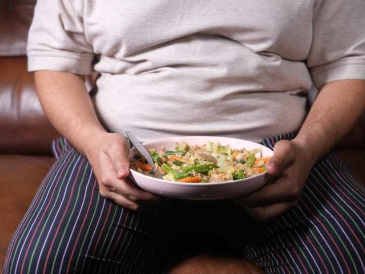 Persona obesa con piatto di cibo